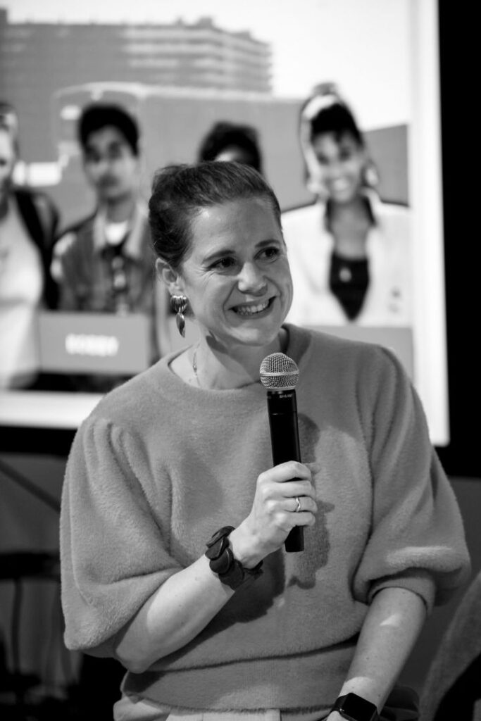 Marjolein Sprenger als dagvoorzitter met microfoon tijdens evenement